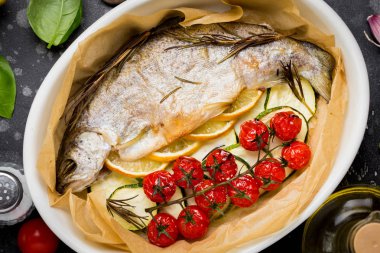 Kabak, domates şube, biberiye ve limon ile seramik pişirme çanağı içinde pişmiş beyaz alabalık balık. Sağlıklı diyet gıda