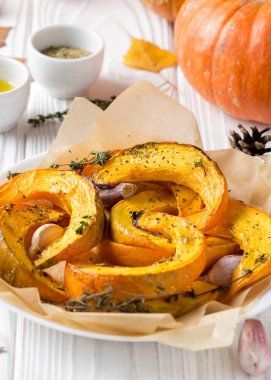 Kekik, zeytinyağı ve sarımsak, lezzetli sonbahar yemek pişmiş kabak. Beyaz ahşap arka plan üzerinde