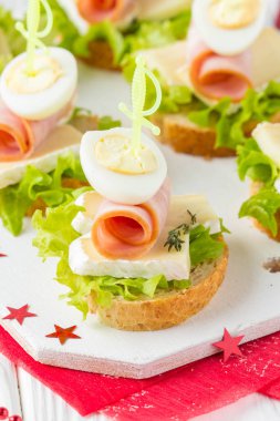 Noel kanepeler üzerinde brie veya Camembert peyniri, jambon ve bıldırcın haşlanmış yumurta ile ekmek. Yeni yıl'ın masada güzel tanıtımı. Stick lezzetli starter