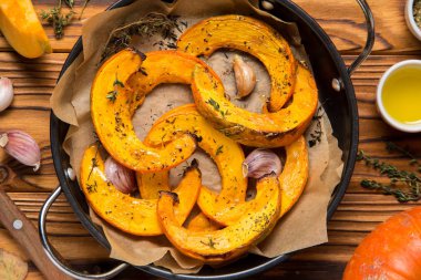 Kekik, zeytinyağı ve sarımsak, lezzetli sonbahar yemek pişmiş kabak. Koyu ahşap arka plan üzerinde