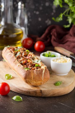 Baget bolognese yahni, kıyma, domates ve peynir ile doldurulmuş. Lezzetli bir öğle yemeği İtalyanca, lezzetli aperatifler, koyu arka plan üzerinde ev yapımı sandviç