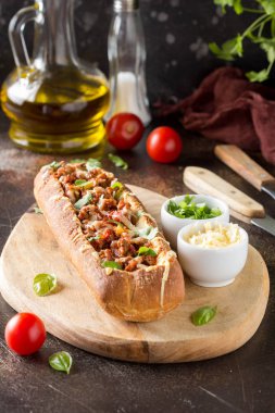 Baget bolognese yahni, kıyma, domates ve peynir ile doldurulmuş. Lezzetli bir öğle yemeği İtalyanca, lezzetli aperatifler, koyu arka plan üzerinde ev yapımı sandviç