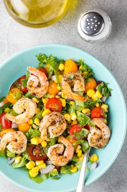 Mısır, yağda kızartılmış karides, cherry domates, kırmızı soğan ve mavi tabak taze lezzetli yemek, sağlıklı gıda içinde marul salatası