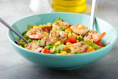 Mısır, yağda kızartılmış karides, cherry domates, kırmızı soğan ve mavi tabak taze lezzetli yemek, sağlıklı gıda içinde marul salatası