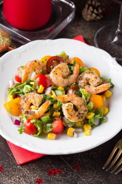 Mısır, yağda kızartılmış karides, cherry domates, kırmızı soğan ve beyaz tabakta marul salatası. Koyu arka plan üzerinde Noel partisi için meze