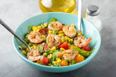 Mısır, yağda kızartılmış karides, cherry domates, kırmızı soğan ve mavi tabak taze lezzetli yemek, sağlıklı gıda içinde marul salatası