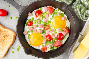 Jambon, domates ve yeşil soğan ile siyah tavada kızarmış yumurta. Kızarmış ekmek ve tereyağı ile lezzetli Breakfast. Klasik İngilizce