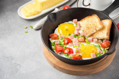 Jambon, domates ve yeşil soğan ile siyah tavada kızarmış yumurta. Kızarmış ekmek ve tereyağı ile lezzetli Breakfast. Klasik İngilizce