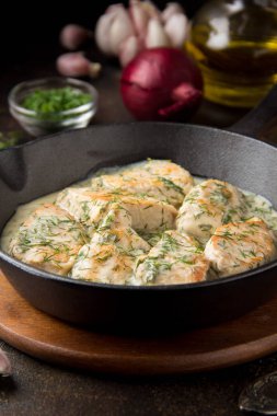 Tavuk fileto veya dereotu ve kalın sos ile koyu arka plan üzerinde siyah dökme demir Tavada sarımsak ile krem soslu hindi göğsü. Lezzetli ev yapımı yiyecek