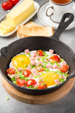 Jambon, domates ve yeşil soğan ile siyah tavada kızarmış yumurta. Kızarmış ekmek ve tereyağı ile lezzetli Breakfast. Klasik İngilizce
