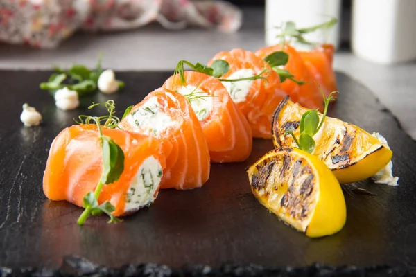 Salmon rolls stuffed with cream cheese and herbs, beautiful snack, elegant food for menu. Tasty dish