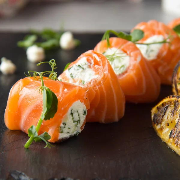 Salmon rolls stuffed with cream cheese and herbs, beautiful snack, elegant food for menu. Tasty dish