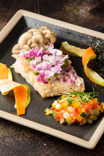 Fried white fish fillet with flowers, vegetables, mushrooms and tartare. Beautiful restaurant serving, elegant food
