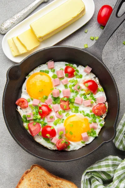 Jambon, domates ve yeşil soğan ile siyah tavada kızarmış yumurta. Kızarmış ekmek ve tereyağı ile lezzetli Breakfast. Klasik İngilizce