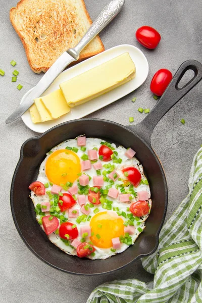 Jambon, domates ve yeşil soğan ile siyah tavada kızarmış yumurta. Kızarmış ekmek ve tereyağı ile lezzetli Breakfast. Klasik İngiliz öğle yemeği. Kopya alanı