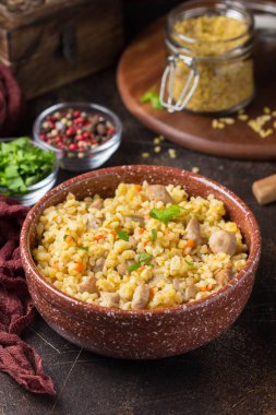 Bulgur with turkey, pork or beef. Eastern dish of rice, delicious traditional food. Stewed meat with grits. Pilaf on dark background clipart