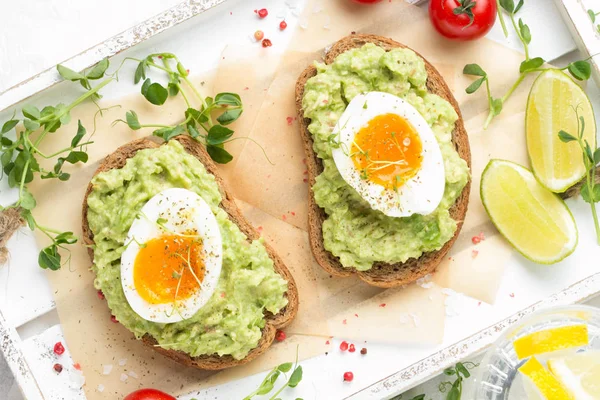 Toast met avocado puree en zachtgekookt ei op witte dienblad, liqu — Stockfoto