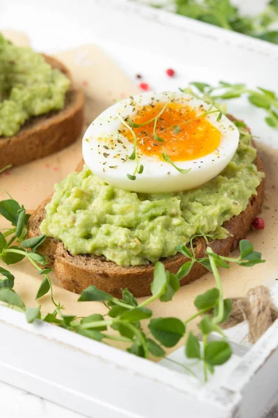 Toast met avocado puree en zachtgekookt ei op witte dienblad, liqu — Stockfoto