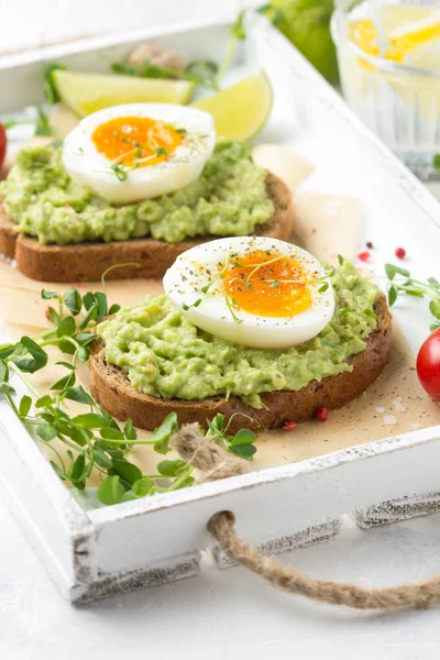 Beyaz tepside avokado püresi ve yumuşak haşlanmış yumurta ile tost, sıvı — Stok fotoğraf