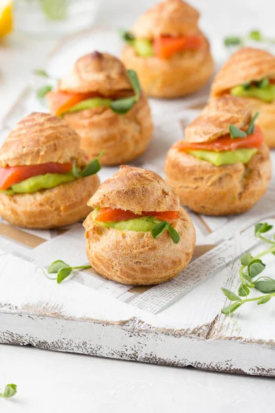 Snack cakes profiteroles with green pea cream and salmon red fis — Stock Photo, Image