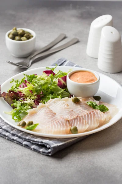 Rodajas finas de pescado ahumado salado con hojas de lechuga y salsa . —  Fotos de Stock