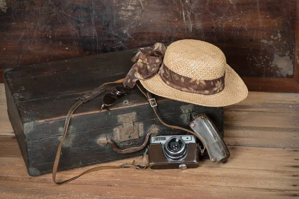 Travel concept with Vintage suitcase old camera on wooden floor.