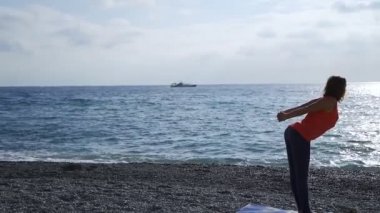 Güneş doğarken bir plajda yoga yaparken deniz kenarında kız