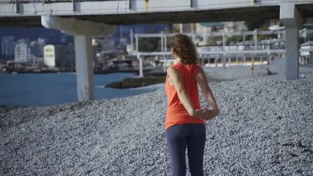 Meisje in de buurt van de zee doet yoga op een strand bij zonsopgang — Stockvideo