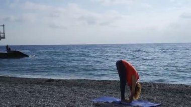 Güneş doğarken bir plajda yoga yaparken deniz kenarında kız
