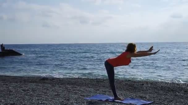Flicka nära havet gör yoga på en strand vid soluppgången — Stockvideo
