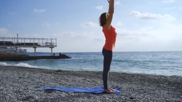 Flicka nära havet gör yoga på en strand vid soluppgången — Stockvideo