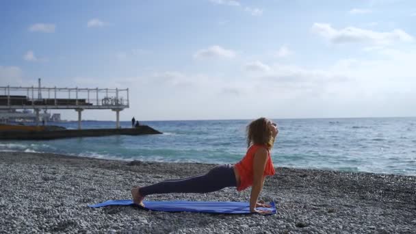 Güneş doğarken bir plajda yoga yaparken deniz kenarında kız — Stok video