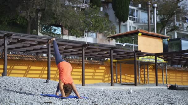 Meisje in de buurt van de zee doet yoga op een strand bij zonsopgang — Stockvideo
