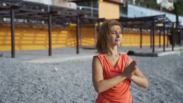 Chica cerca del mar haciendo yoga en una playa al amanecer — Vídeo de stock