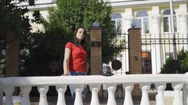 Kamerada poz veren güzel kız. Yeşil gözlü, kırmızı tişörtlü ve siyah şapkalı genç bir kız yazın kameraya poz veriyor.