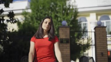 Kamerada poz veren güzel kız. Yeşil gözlü, kırmızı tişörtlü ve siyah şapkalı genç bir kız yazın kameraya poz veriyor.