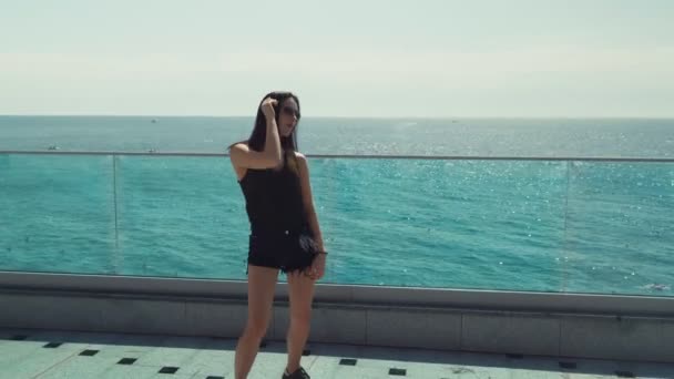 美丽的黑发女郎 戴着太阳镜 在大海4K的背景下摆出姿势 在镜头前跳舞 — 图库视频影像