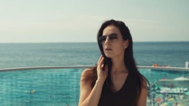 Güneş gözlüklü güzel esmer kız kameraya poz verip dans ediyor.