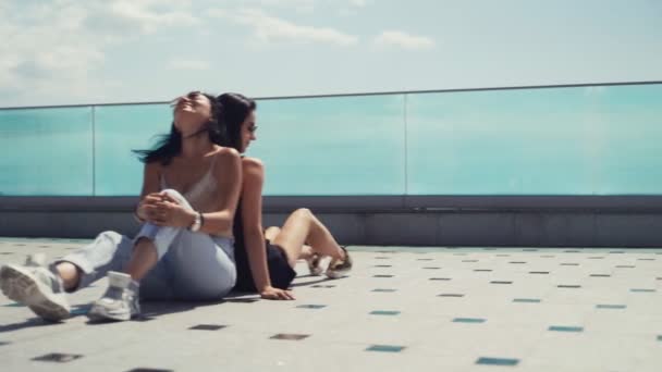 Dos Guapas Chicas Morenas Gafas Sol Sentadas Espalda Sonriéndose Mutuamente — Vídeos de Stock