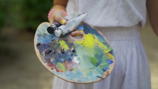 パレット上の女の子アーティストは 古い小さな池4Kの風景をペイントするために小さな塗料を広げる — ストック動画