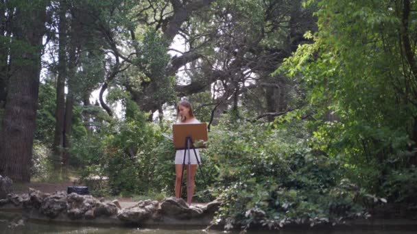 公园里的女艺术家用油画描绘了一个小的旧池塘 有莲花4K — 图库视频影像