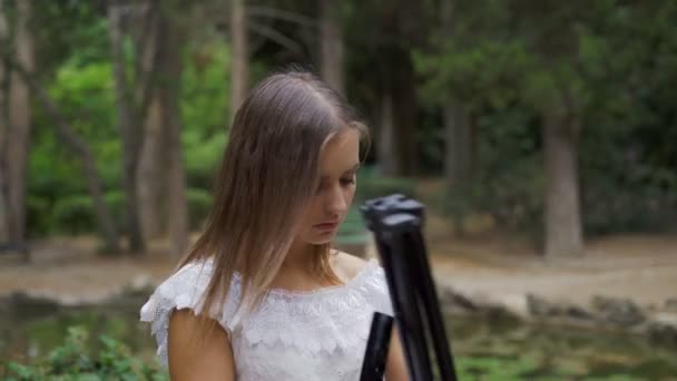 Fille artiste prépare palette de papier et pinceaux pour la peinture de paysage dans le parc avec un petit étang 4k — Video