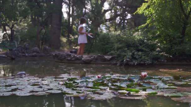 Fille artiste dans le parc peint un paysage avec de l'huile peint un petit vieil étang 4k — Video