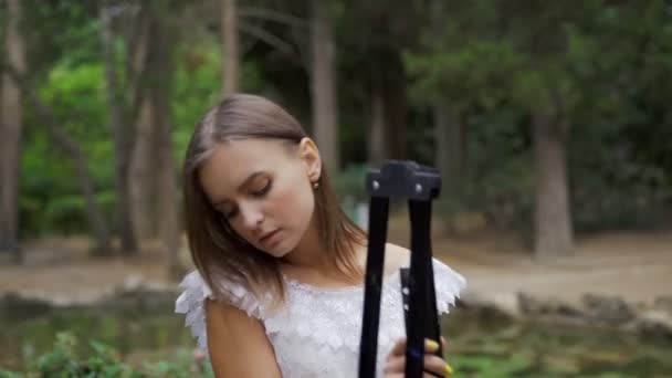 女の子アーティストは、小さな池4kで公園で風景画のための紙パレットやペイントブラシを準備します — ストック動画