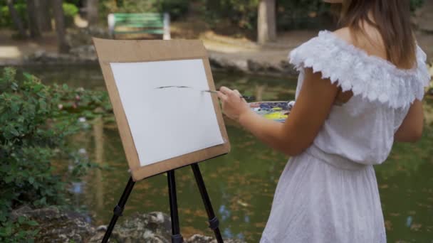 Lány művész a parkban fest a táj Olajfestékek egy kis öreg tó 4k — Stock videók