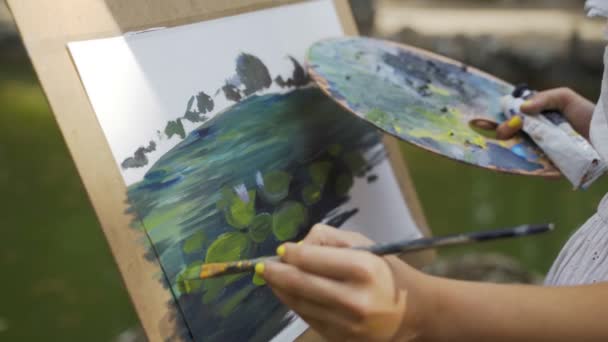 Girl artist in the park paints a landscape with oil paints a small old pond 4k — Stock Video