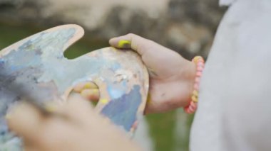 Bir palet kız sanatçı peyzaj boyama 4k için küçük boyalar yayılır
