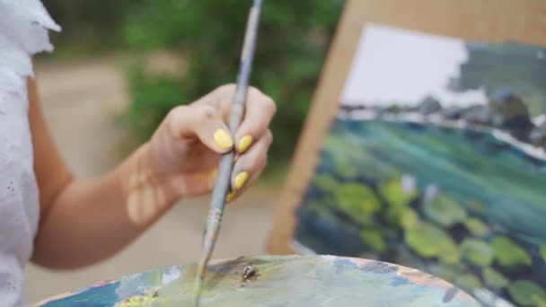 Girl artist in the park paints a landscape with oil paints a small old pond 4k — Stock Video