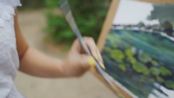 Menina artista no parque pinta uma paisagem com pinturas a óleo uma pequena lagoa velha 4k — Vídeo de Stock