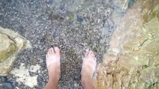 男性の足は海の波で洗われます 若者の視点 男の裸足は石の海岸4Kに立っています — ストック動画